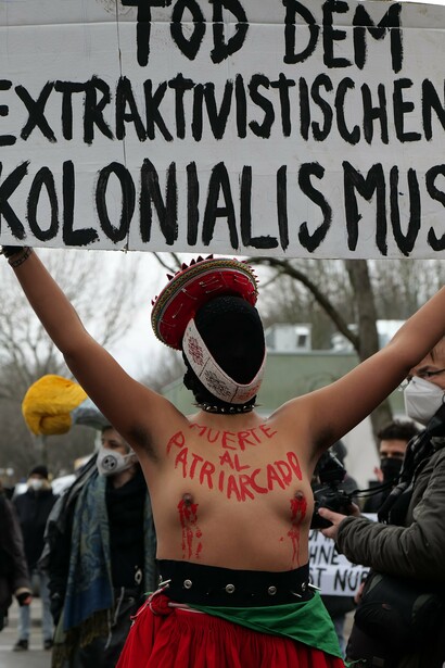 Manifestante sostiene un cartel que dice "Muerte al colonialismo extractivista" durante una marcha en Berlín, Alemania, a raíz de la contaminación producto de la industria petrolera, 2022