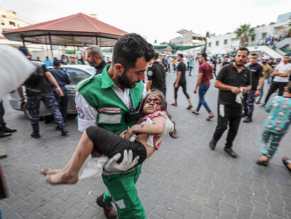 Medics carry an injured Palestinian child into Al-Shifa Hospital in Gaza City after an Israeli airstrike on October 11, 2023, highlighting the impact of war on civilians
