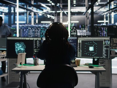 A computer scientist working in a data center monitors AI network structures through node-tree visualization and data flow systems