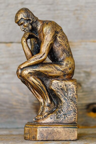 The 'Thinking Man' statue portrays a deeply reflective individual, poised in contemplation