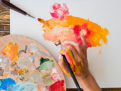 A top-down view of an artist painting with their hands, showcasing the vibrant colors and the creative process in action