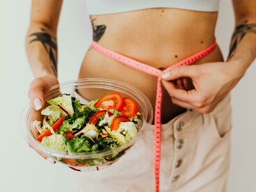 A toned woman enjoying a vegetable salad as part of her weight-loss journey