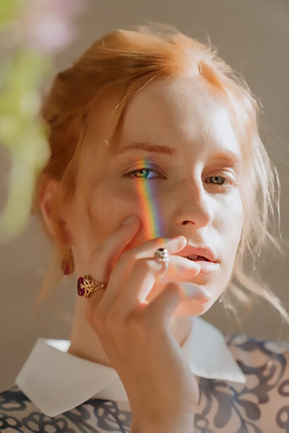 An enchanting photograph capturing the elegance of a woman, with a vibrant rainbow gracefully hovering over her eyes on the right side of her face