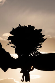 Side view of a couple holding a bouquet of flowers together