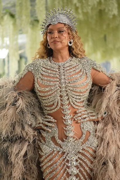 Beyoncé in Olivier Rousteing, wearing a crystal-encrusted skeletal gown with a jeweled crown and dramatic feathered coat during the 2026 Met Gala
