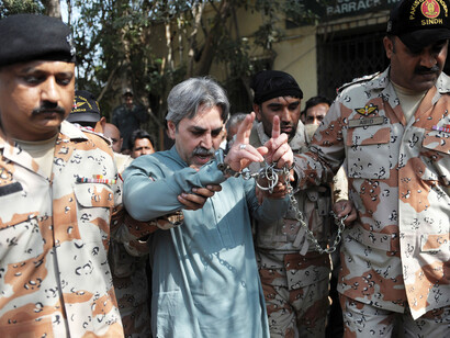 Pakistani paramilitary officials escort handcuffed Aamir Khan, the leader of Muttahida