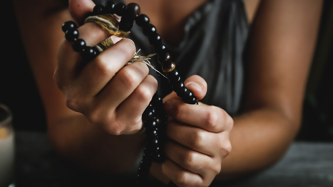 A woman holding prayer beads, deeply engaged in spiritual reflection and prayer