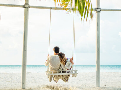 A couple relaxes in a swing on the beach