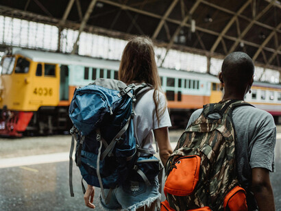 Two female friends walk side by side through a train station, ready for their next adventure abroad