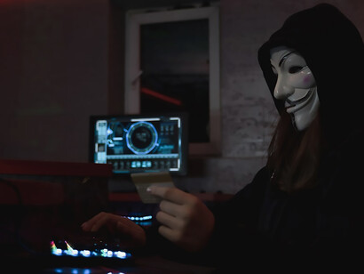 A hacker donning a Vendetta mask engages in illicit activities on a computer