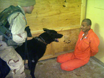 An American soldier, his dog, and a detainee at the Abu Ghraib prison in Iraq, 2003