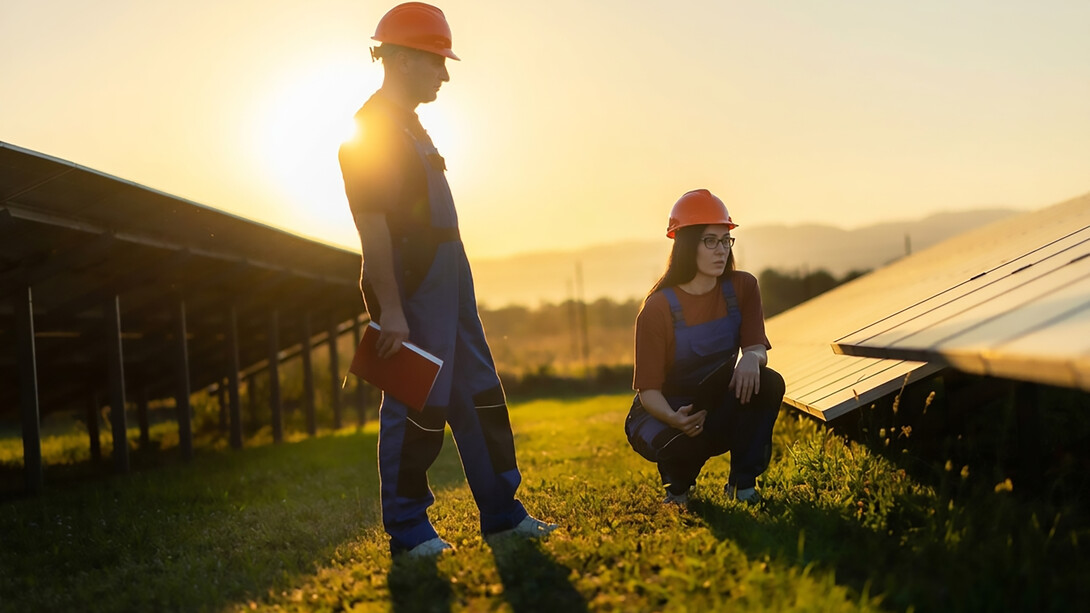 Technicians install solar panels on the roof of a residential building