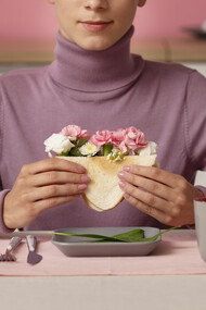 Adult seen from the front holding a sandwich filled with flowers