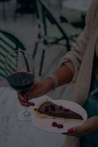 At the wine table, a woman delights in a selection of cakes, enhancing her experience with fine wine pairings