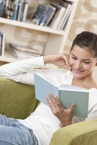 Una chica leyendo un libro en casa