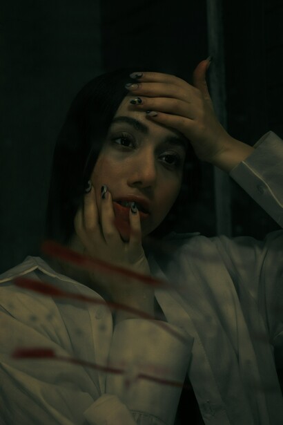 A sad woman standing in front of a mirror, lost in quiet reflection