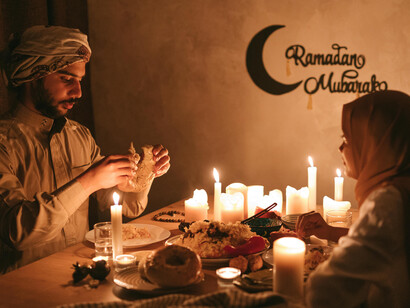 A Muslim couple sharing a quiet, candlelit dinner during Ramadan