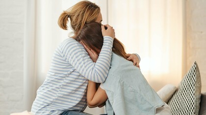 Woman hugging crying tween child