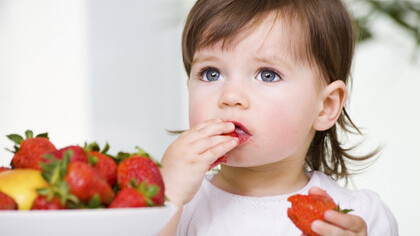 Una niña comiendo fresas