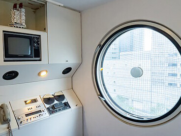 A Nakagin Capsule Tower capsule on display near Roppongi Hills Mori Tower in Tokyo, Japan, highlighting its small scale living space
