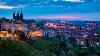 Prague’s historic rooftops and landmarks illuminated against the twilight sky, representing the city’s magical character