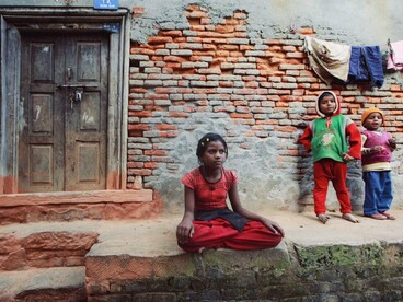 A group of children outside a deteriorating house, reflecting the urgent need to direct wealth toward improving everyday lives