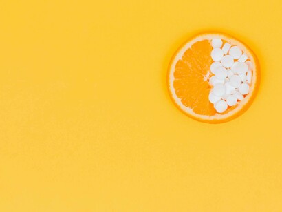 An orange slice with its fruit in one half and in the other half medication to treat the vitamin D deficiency
