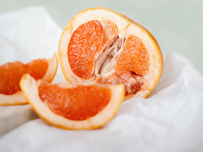 A grapefruit sliced in half and some two small slices