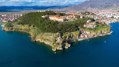Scenic aerial view of Ohrid, North Macedonia, nestled amidst mountains and overlooking Lake Ohrid on a bright sunny day