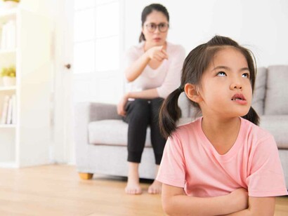 A mother sitting on her couch is scolding her child who seems to be extremely annoyed with her mother's parenting approach which borderlines on the authoritarian side