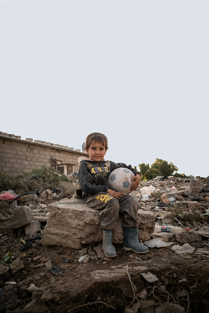 A boy seated with a football in Baghdad, Baghdad Governorate, Iraq
