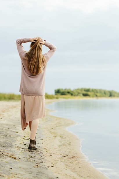 A woman walking by the beach shore, taking time to relax and time for herself, exercise is good for your mental health