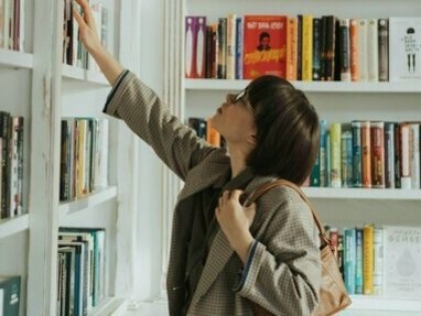 Mulher escolhe livros para ler. Viajamos com o livro para a frente e para trás; para o recôndito e para a fantasia e podemos criar um mundo só nosso a partir de muitos que nos são oferecidos pelo escritor, num só livro!