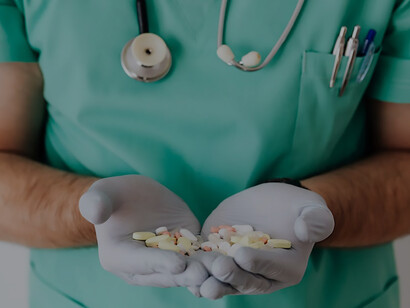 A doctor grasps a diverse assortment of medications in their hand