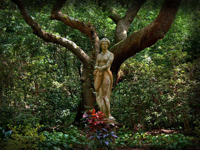 A garden sculpture in front of an oak tree