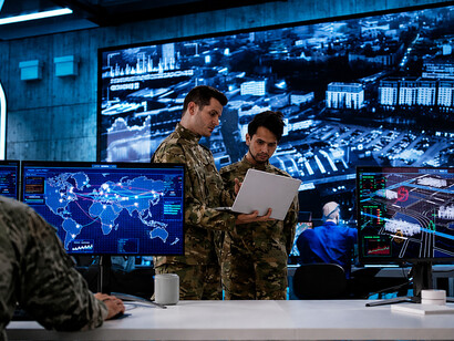 Military personnel using advanced technology to analyze and monitor data in a command center