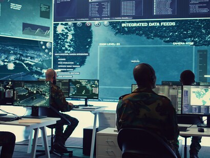 A military team operates in a reconnaissance control center, surrounded by multiple monitors in a high-security cyber defense environmen