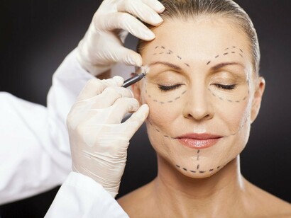 Un cirujano prepara una operación estética en la cara de una mujer