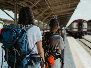 Two female friends explore a European city together, backpacks on and maps in hand