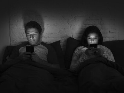 Pareja revisando sus redes virtuales en la cama. Un uso excesivo y no racional de las RV puede ocasionar problemas de dependencia, adicción y miedo