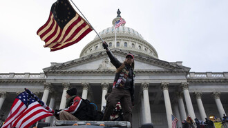 Hombre hondea una bandera de Estados Unidos en el Asalto al Capitolio el 6 de enero de 2021 en Washington D.C.