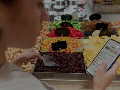Woman uses smartphone to scan barcodes for nutritional information while shopping for various vegetables