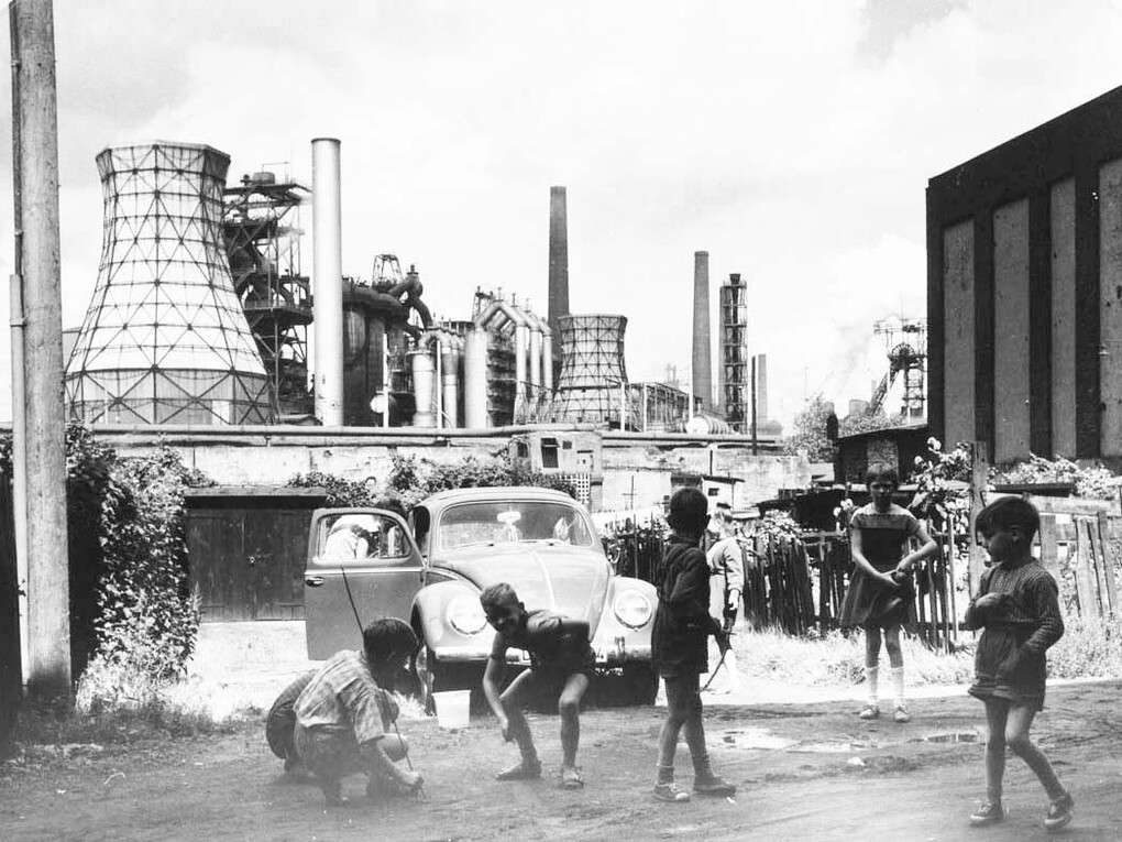 Rudolf Holtappel (Münster, Germania, 1923 -
 Duisburg, Germania, 2013) - Duisburg Bruckhausen, Ebertstrasse con stabilimento metallurgico - August Thyssen, 1959 Duisburg 
Stampa ai sali d’argento, 29,1 × 37,8 cm - Estate of the Artist
