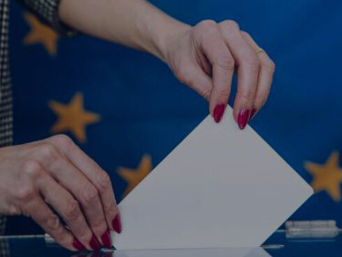 Voters casting their ballots at a European Union election, with the EU flag prominently displayed in the background