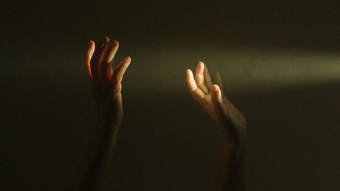 Mani che raggiungono la luce che filtra da una fessura