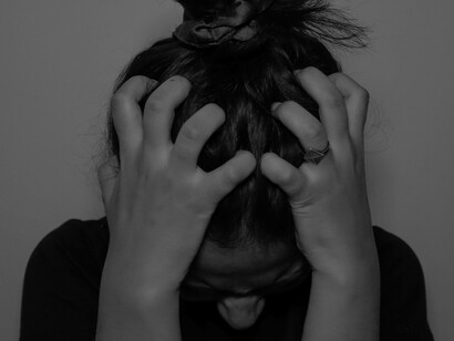 A young person at the point of melting down from the stress has their hands on their head and fingers pressing down on her their skull