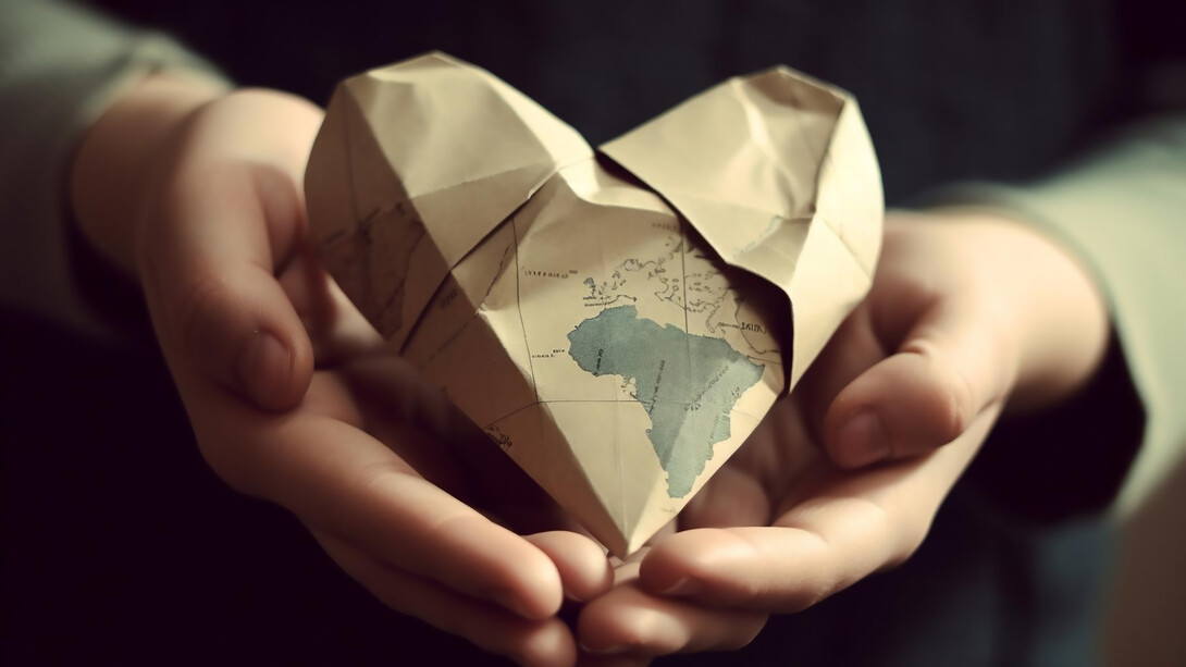Encircling the globe with love, hands cradle a map in the shape of a heart, symbolizing a shared commitment to fostering global harmony