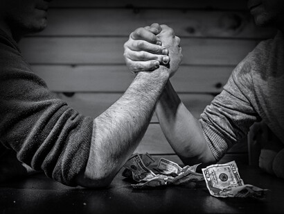 Dos hombres compiten a pulso por unos cuantos billetes