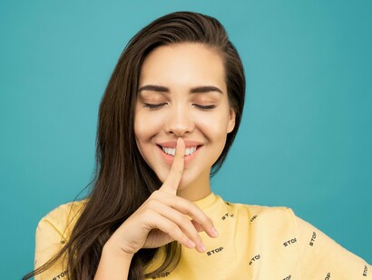 A woman smiling with her eyes closed is calling for silence