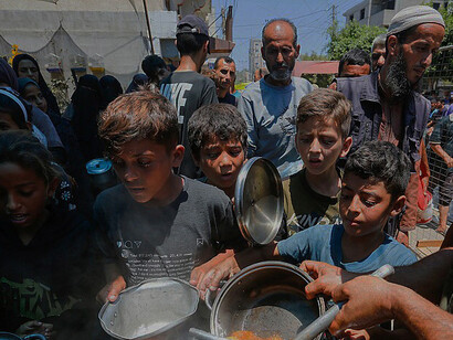 Displaced Palestinians gather in Deir al-Balah, Gaza Strip, to receive food assistance, highlighting the ongoing humanitarian needs of civilians affected by conflict and displacement